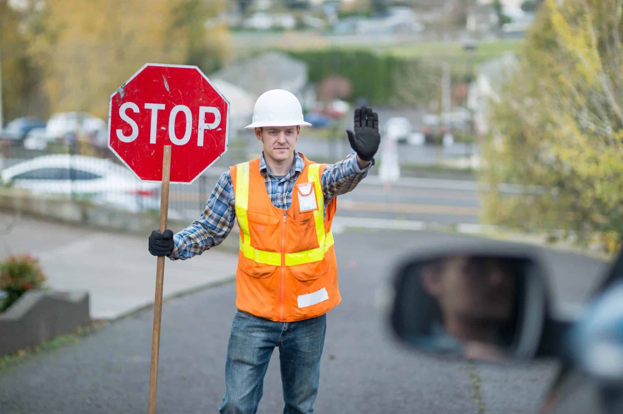 Flagger holds up stop sign for traffic in construction zone